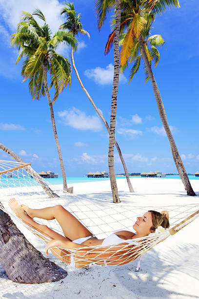 istock Woman lying in hammock near the palm trees. 157604287