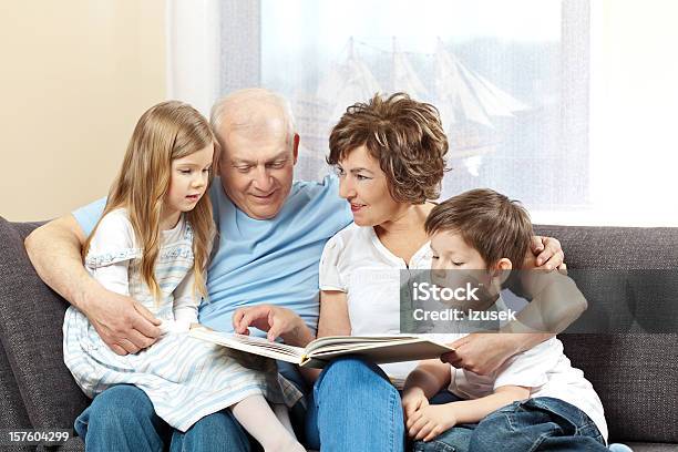 Grandparents With Grandchildren Reading Book Stock Photo - Download Image Now - 6-7 Years, 60-64 Years, 60-69 Years