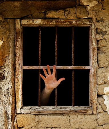 human hand emerging from prison bars