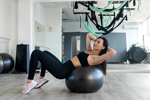 Young attractive slim woman doing exercise with fitball at fitness center. Sport as lifestyle