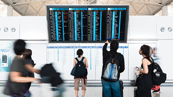 Motion blur Asian tourist traveler people walk at Hong Kong international airport terminal, arrival departure information board. Oversea transportation, airline transport business, Asia travel concept