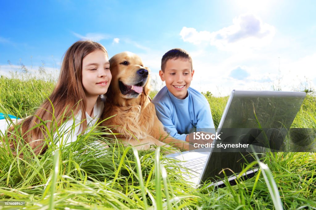 Bambini con il cane sul prato a riposo. - Foto stock royalty-free di Accudire