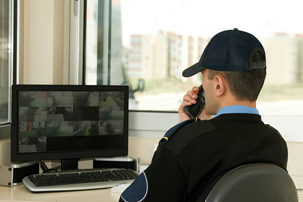 Security worker speaking on radio while watching monitor stock photo