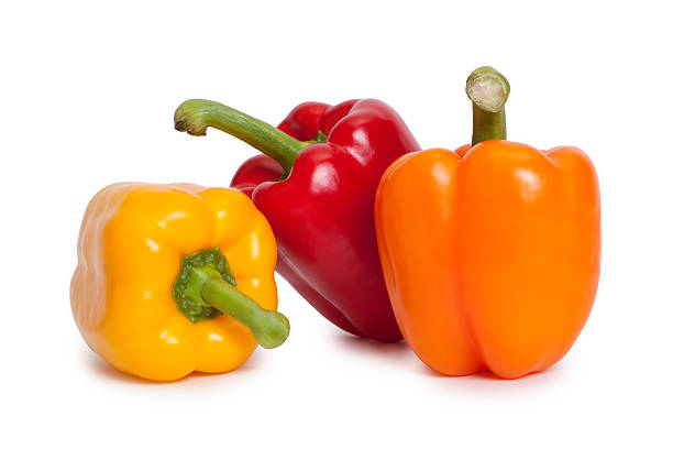 Three different coloured peppers arranged in a group.