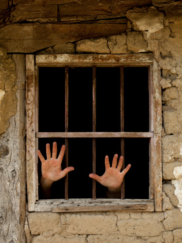 human hands emerging from prison bars