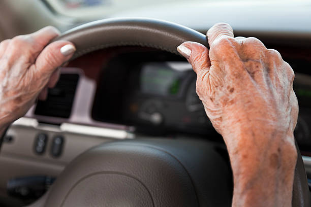 senior woman hands, driving car, steering wheel stock photo