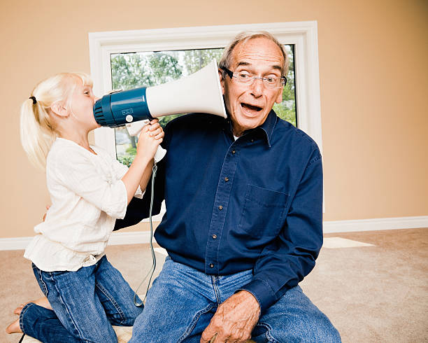 Announcement Little Girl Talking to Deaf Grandpa little girl is making a loud announcement. communicating with her deaf grandpa through a megaphone.  hearing loss photos stock pictures, royalty-free photos & images