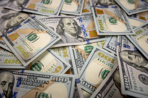 istock Close-up stack of hundred dollar bills isolated on black background. 1576069642
