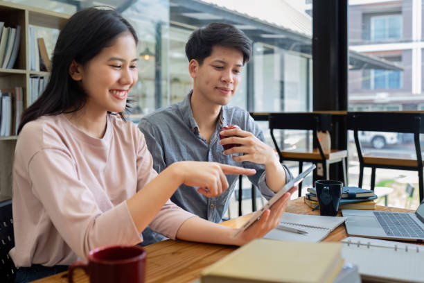 istock Two Asian students learning together with a laptop and tutor together at cafe 1576072143