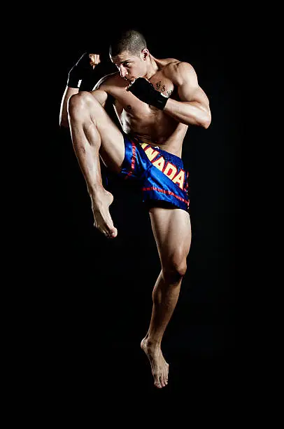 Muay Thai fighter isolated on black background.