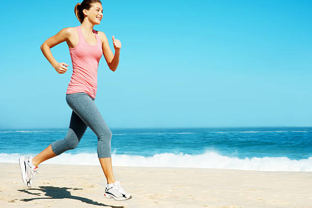 istock Side view of a young lady jogging on sea shore 157607349