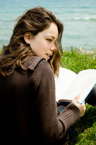 istock Girl reading by the sea 157607503