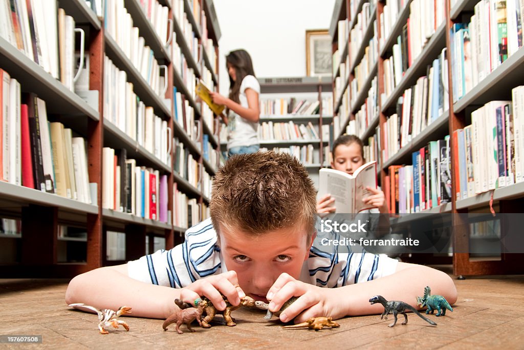 Niño jugando en la biblioteca - Foto de stock de Dinosaurio libre de derechos