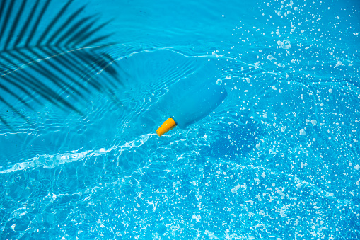 Blue sunblock cream in blue outdoor swimming pool. Copy space, Summer skin care abstract background