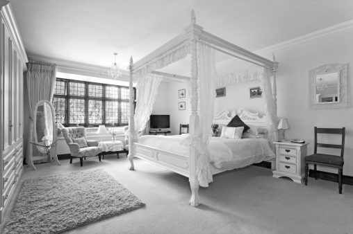 A four poster bed in a traditional country house hotel rendered in black and white with slightly pushed contrast for effect.