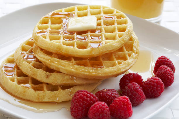 Breakfast plate of waffles and raspberries, butter and maple syrup