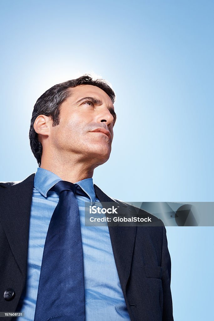 Grave executivo de negócios olhando longe de casa contra o céu azul - Foto de stock de Adulto royalty-free