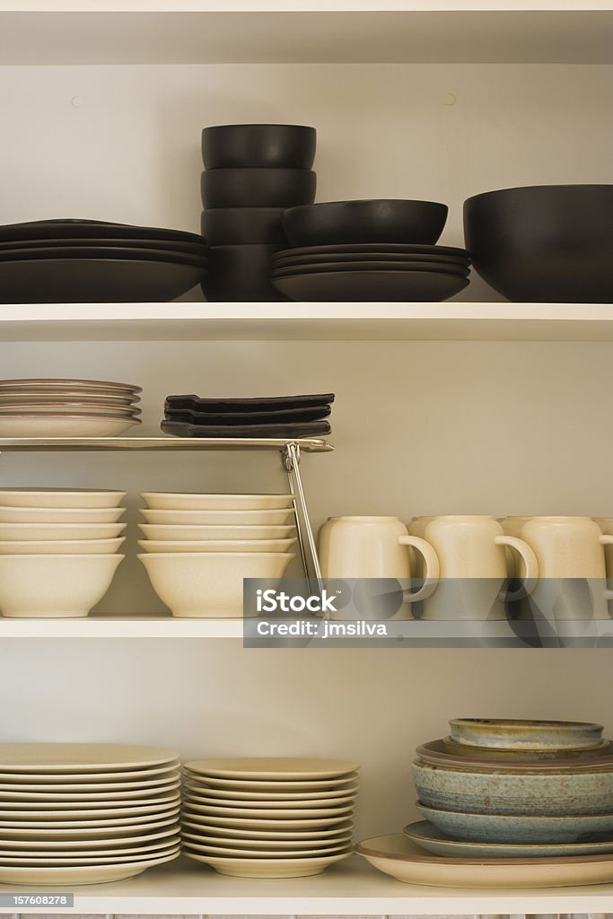 Kitchen cabinet with black and white dishes A detail of a modern kitchen showing shelves storing simple white tableware, Cabinet Stock Photo
