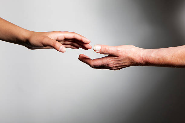 les mains: jeune et vieille mains pour atteindre les uns les autres - laisser partir photos et images de collection