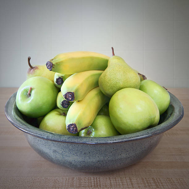 Orange gluss plate with yellow bananas and green apples 
