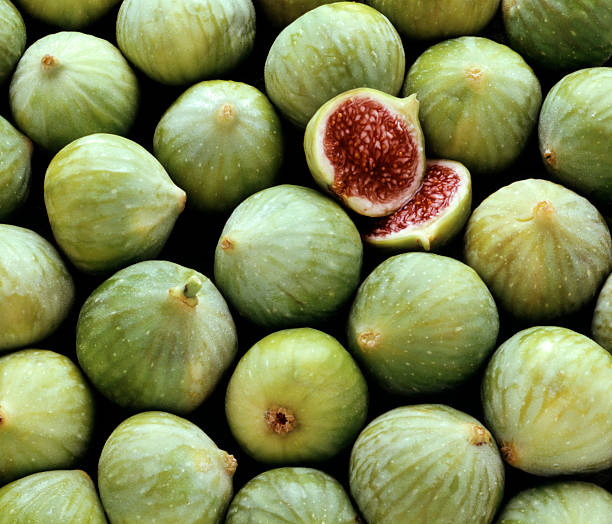 Pile of fresh green figs, one cut open stock photo