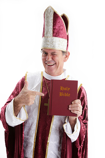 Winking priest pointing to a bible