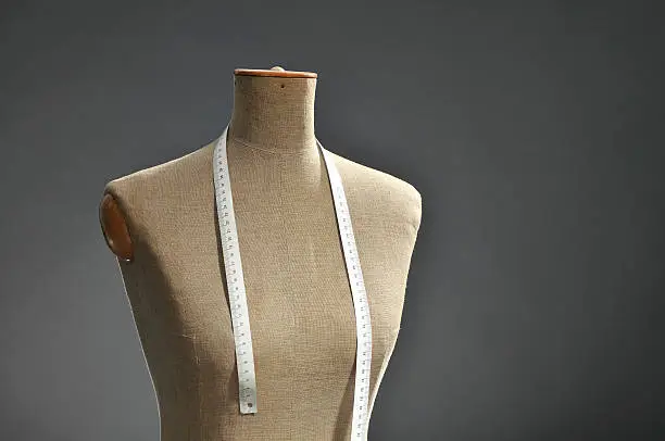 Photo of Retro female tailor's mannequin torso with measuring tape, dark background