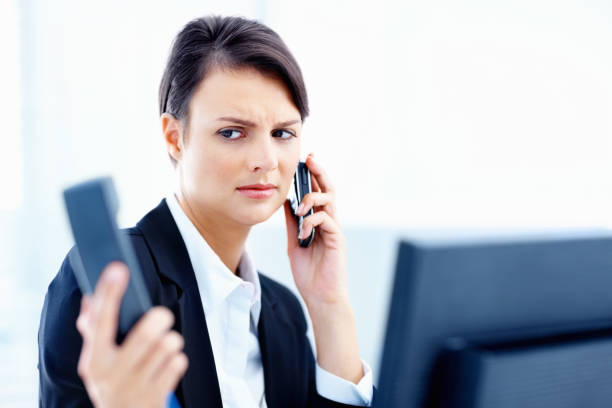istock Secretary holding telephone handset and cellphone at work 157609491