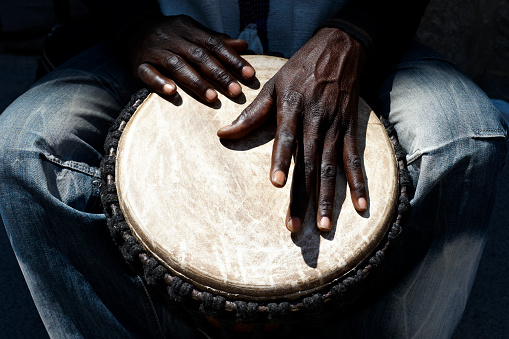 Close up of hands of a black man playing a drum.