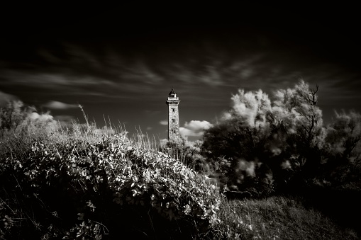 A lighthouse sitting on a high cliff is surrounded by a fog and mist that provides ample room for copy and text.