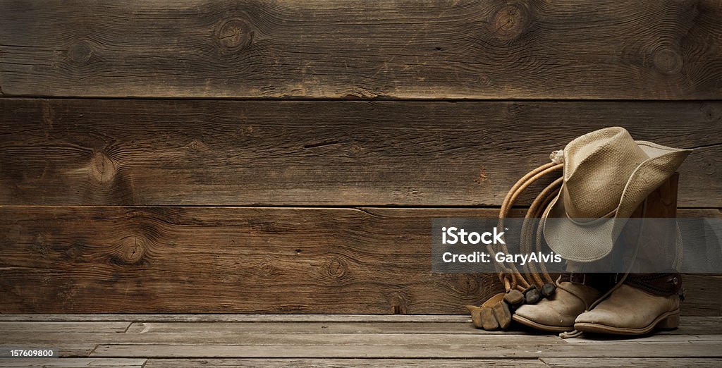 Western barnwood background w/boots,hat,lasso-extra wide Cowboy hat,boots,lasso,spurs and riding gloves on the right side of a plain,weathered,rustic barnwood background.  room for title and/or text. Extra wide and large file size for a banner format.http://www.garyalvis.com/images/wildWest.jpg Wild West Stock Photo