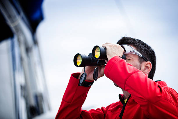 marin avec des jumelles sur voilier - binoculars surveillance direction looking at view photos et images de collection