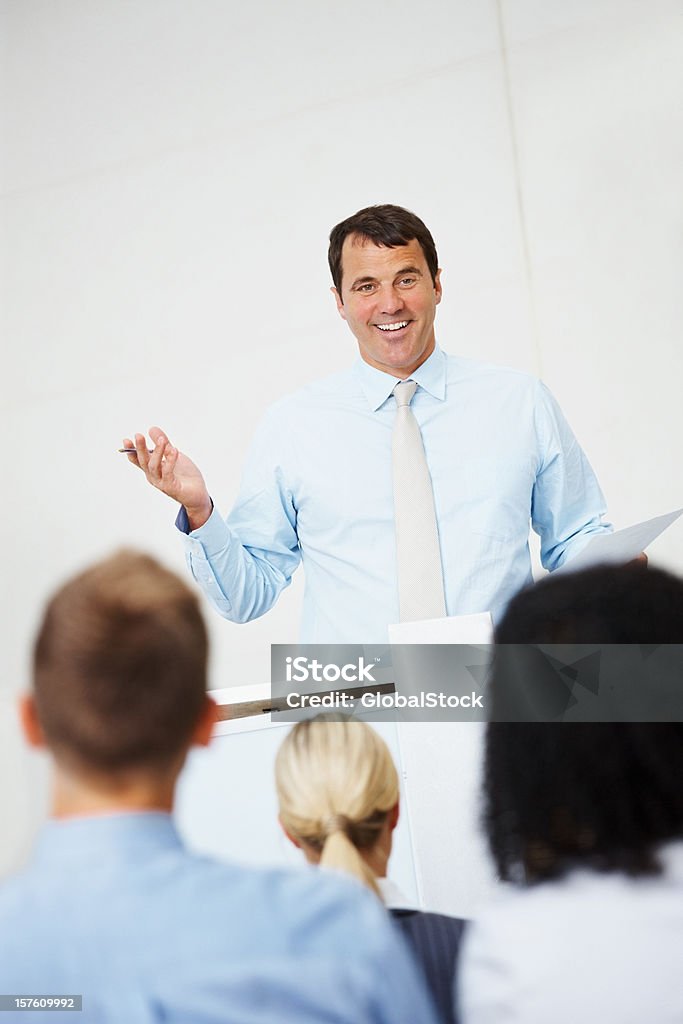 Uomo d'affari sorridente ad un gruppo di persone - Foto stock royalty-free di 20-24 anni