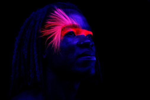 Portrait of man under black lights.  No filters were used to create this effect - this is UV lighting creating the glow in the  makeup and skin. Extremely low light situation with high ISO settings. 
