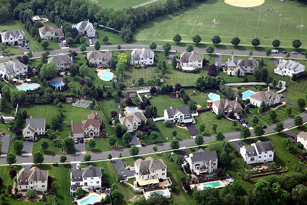 Color DSLR picture of luxury beach vacation houses on the New Jersey shore in Spring Lake.  The houses have manacured green grass lawns and the image has a deep blue sky background.  The street in front and the open sky behind provide ample copy space for text to this horizontal image.  