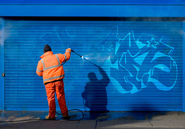 lavare graffiti su una griglia di protezione. - removing foto e immagini stock