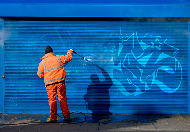 Washing graffiti off a security grill.  absence stock pictures, royalty-free photos & images
