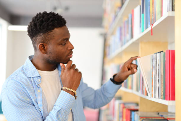 istock African student standing in front of a bookshelf and pointing at a book 1576110409