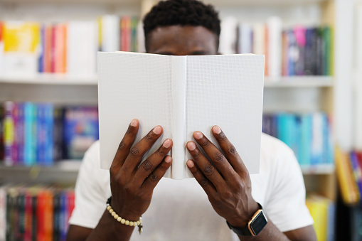Close-up of a man reading a book in a bookstore.