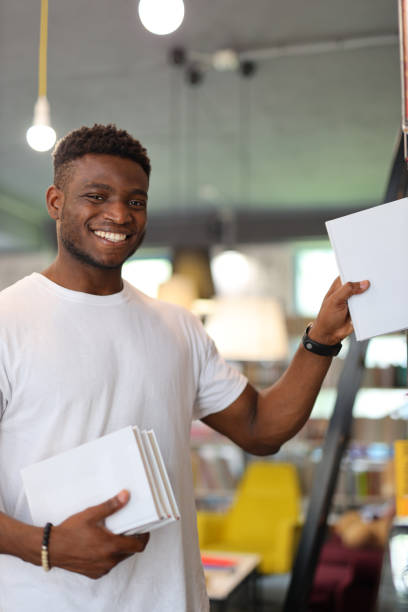 istock Cheerful black guy buys books in the store. 1576112057