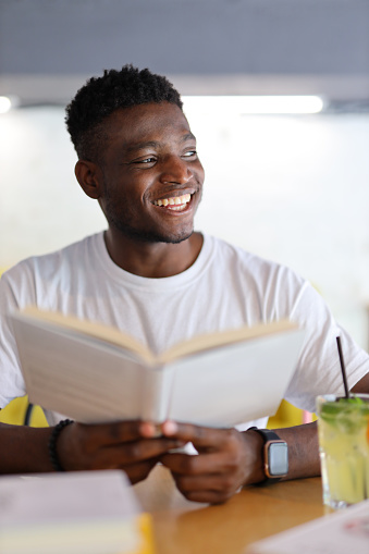 Handsome African man who is holding a book in their hand. He is a young and happy student, business or life who is reading, studying or learning for his education.