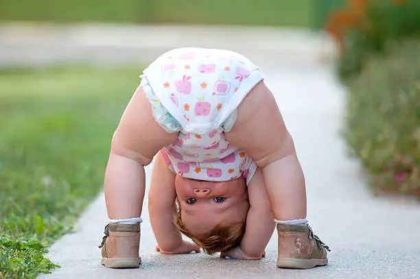 One-year baby girl playing upside down on the street