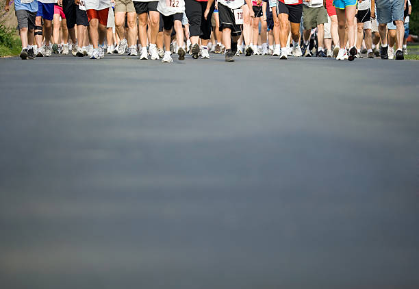 Walker’s Legs with Pavement Foreground A large group of legs in a walking race with a pavement foreground. Depth of field is very shallow with clear focus on the second row of feet only. someone walking sneakers stock pictures, royalty-free photos & images