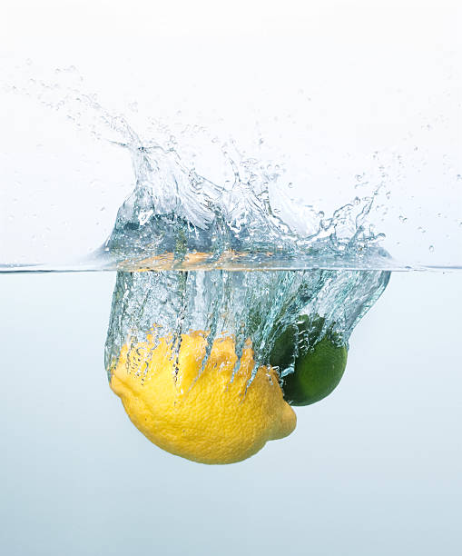 Lemon and lime splashing into the water