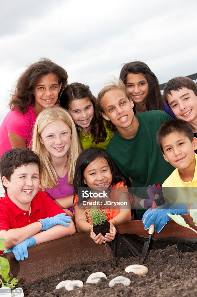 Gruppo di diversi bambini lavorano insieme per piantare un giardino - Foto stock royalty-free di Bambino