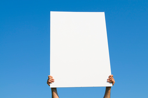 Man holding blank billboard against blue sky,copy space.