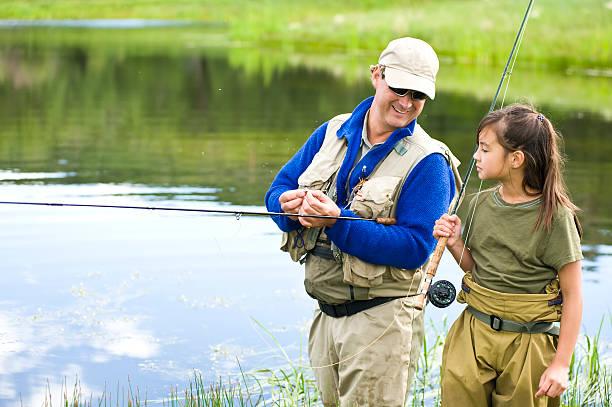 istock Father shows daughter how to hook a fly fishing pole 157611876