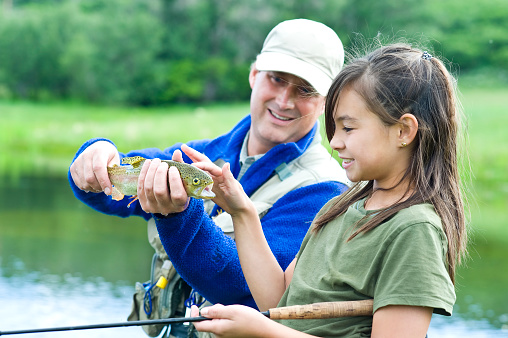 Fly fishing father giving daughter lessons with copy-space