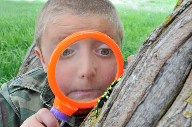 Young boy examines spider with magnifying glass
