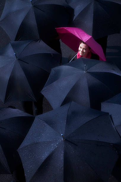 женщина, глядя на солнце разбивая в дождь - standing out from the crowd individuality umbrella contrasts стоковые фото и изображения